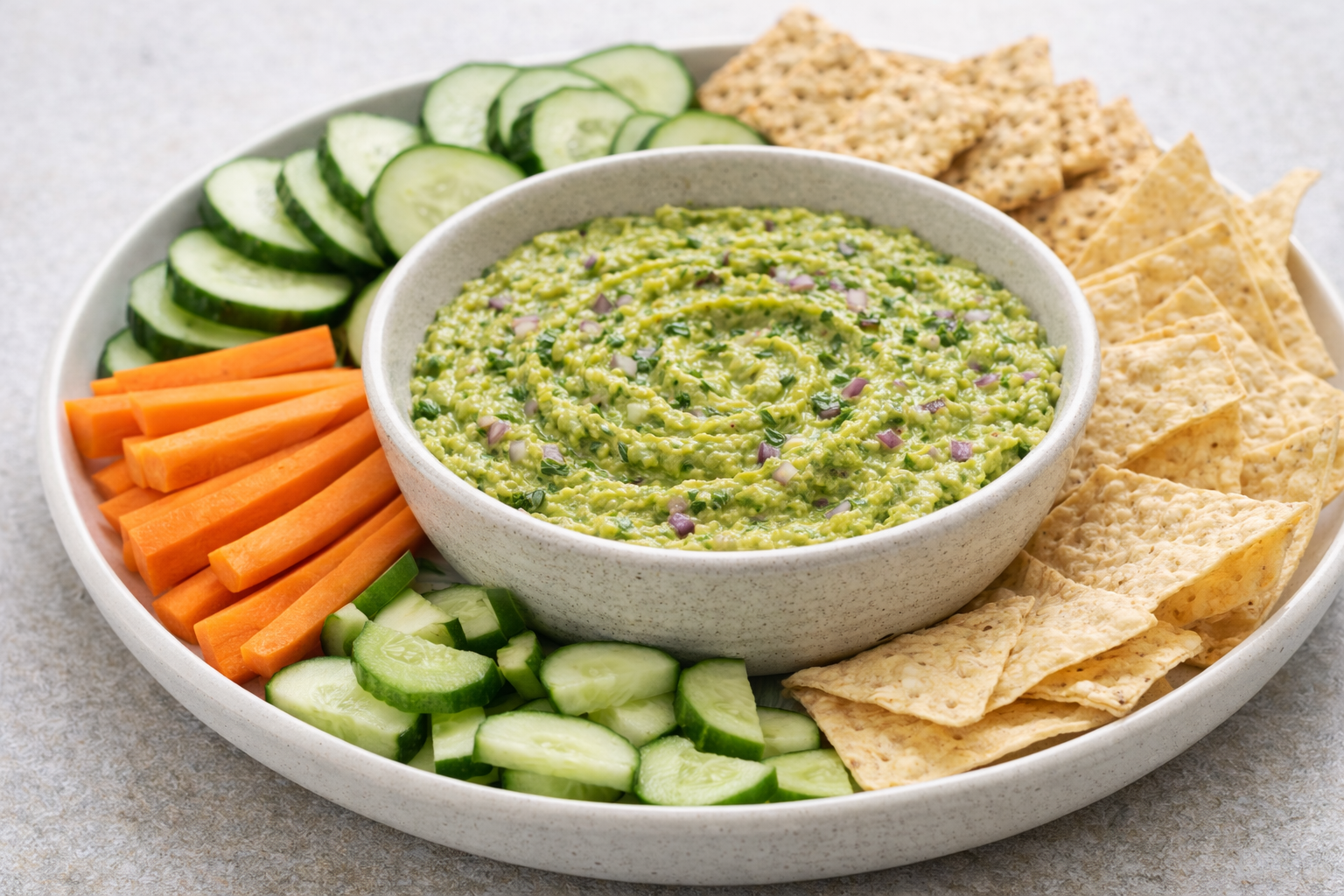 Cannabis-infused creamy avocado dip served with cucumbers, carrots, crackers, and chips