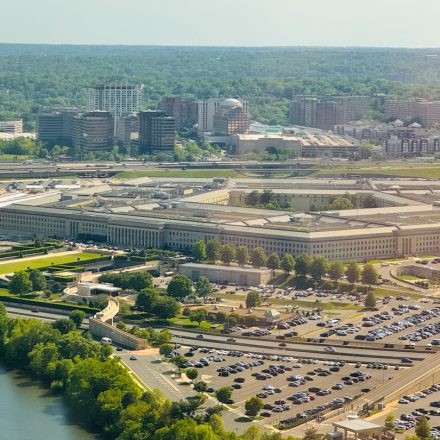 The pentagon building with surrounding parking lot and trees.